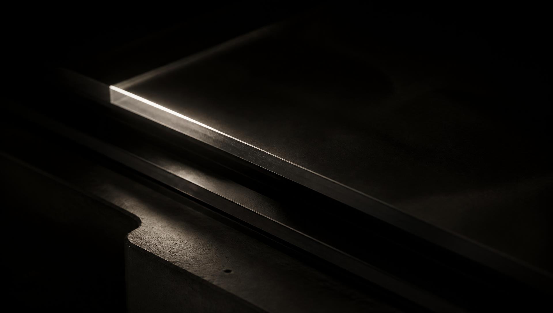 Black glass and concrete edge lit by a single line of light